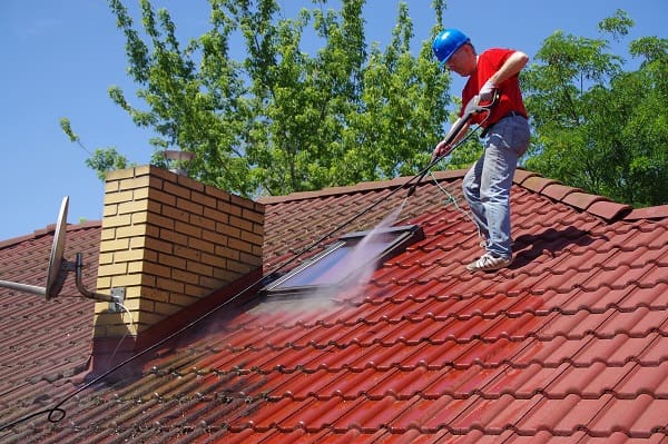 Un professionnel nettoyant le toit en tuiles d'une maison